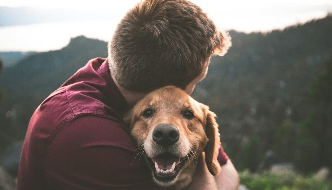 photo of man hugging tan dog