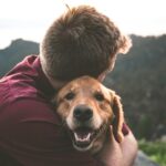 photo of man hugging tan dog